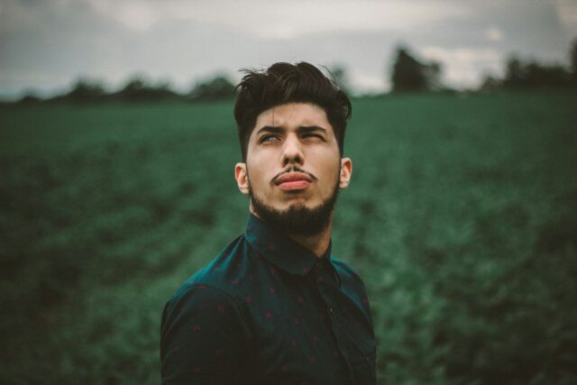 serious man in field looking up