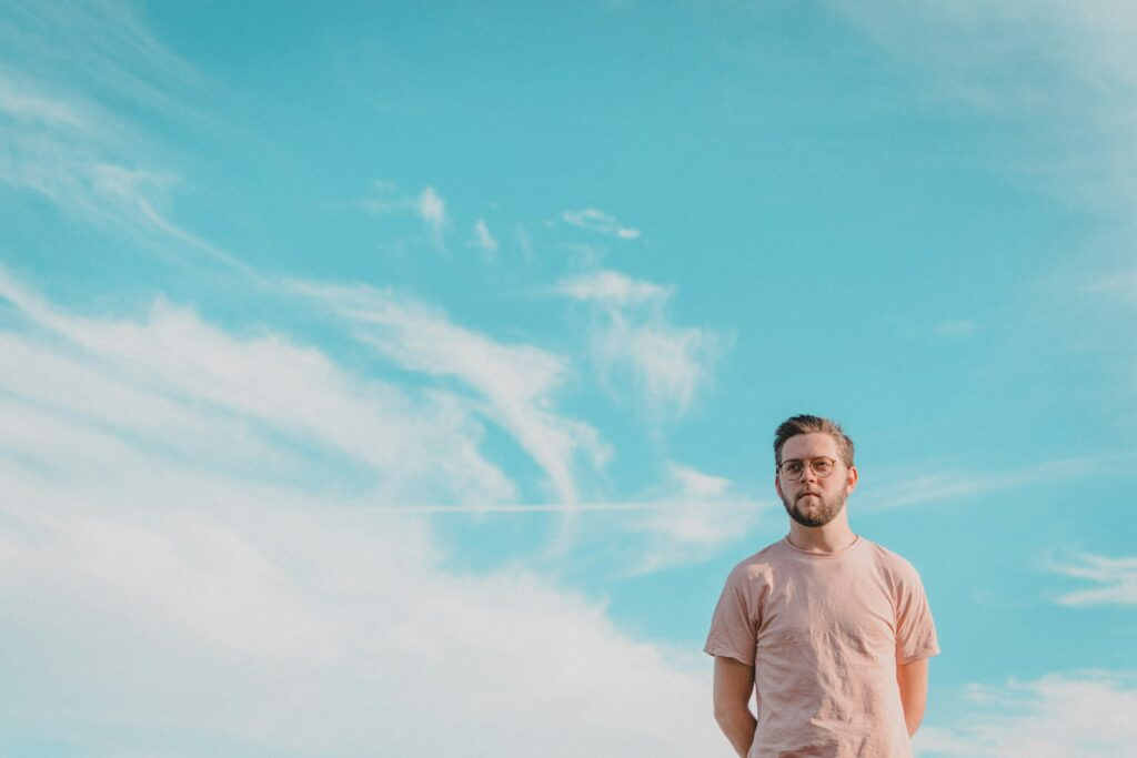 young man standing under blue sky